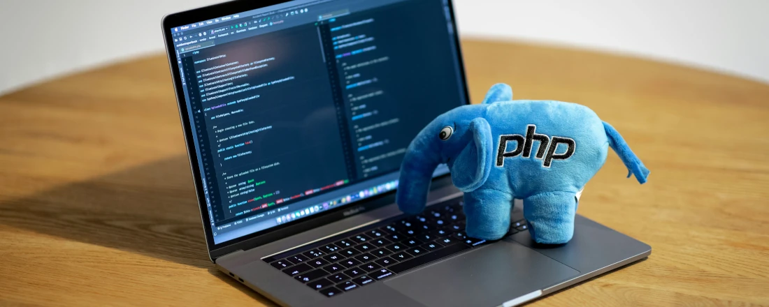 An illustration of a stuffed PHP elephant placed on the keyboard of a laptop.